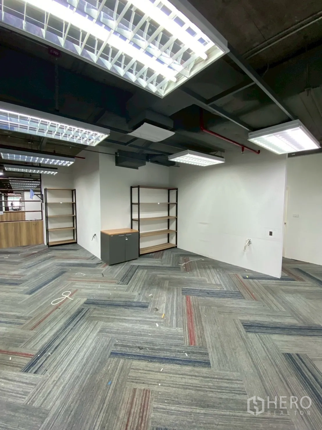 办公室 for rent in Watthana, Bangkok - 角落空间设置置物架与储物柜，顶挂灯具。