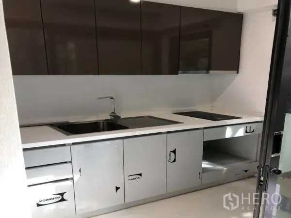 Townhouse for rent in Suan Luang, Bangkok - Modern enclosed kitchen with built-in cabinets, sink and electric cooktop.