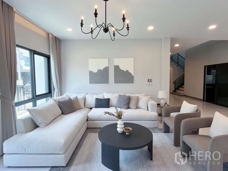 Detached House for rent or sale in Bang Phli, Samut Prakan - Lounge area with L-shaped sofa, armchairs and a black chandelier.