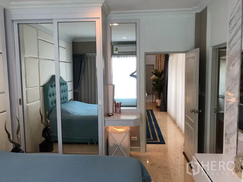Detached House for rent or sale in Saphan Sung, Bangkok - Bedroom with mirrored wardrobes and a vanity beside a bright hallway.