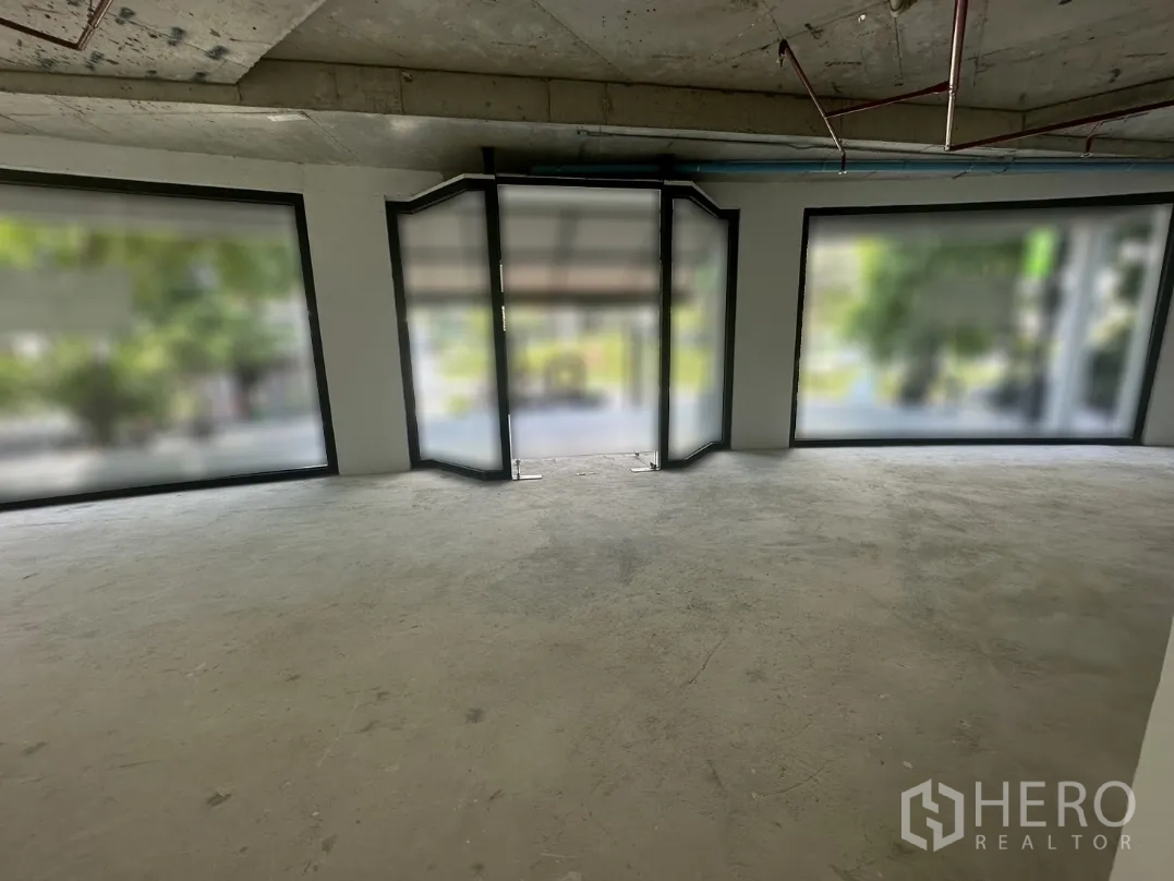 Office Space for rent in Khlong Toei, Bangkok - Shell-condition interior with concrete floor and floor-to-ceiling corner windows.