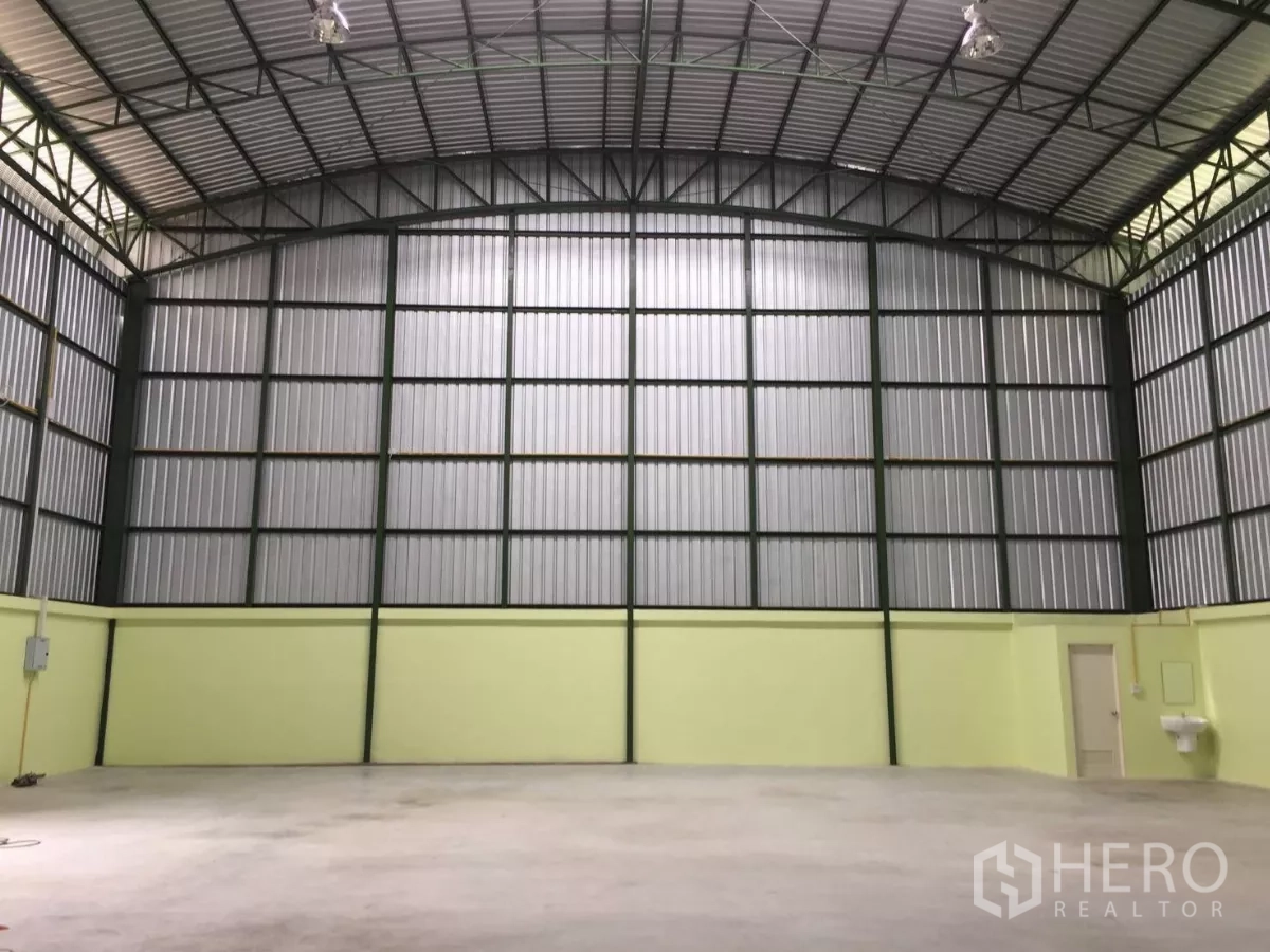 Warehouse for rent in Lat Krabang, Bangkok - High-ceiling warehouse interior with steel trusses, smooth concrete floor, and a service door.