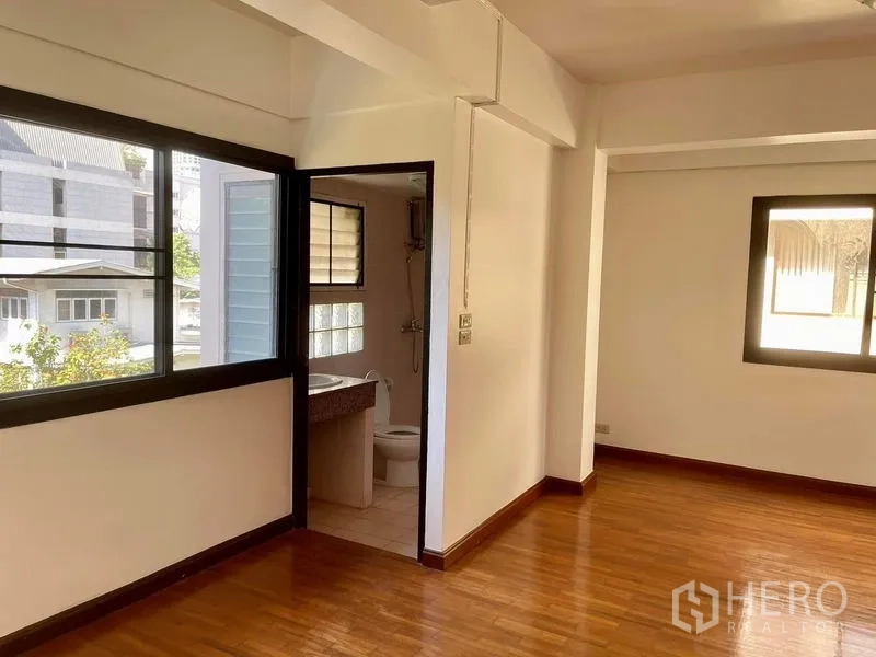 สำนักงานที่บ้าน ให้เช่าในKhlong Toei, Bangkok - ห้องนอนรับแสงดี พื้นไม้ มีห้องน้ำในตัวมองเห็นผ่านประตูเปิด