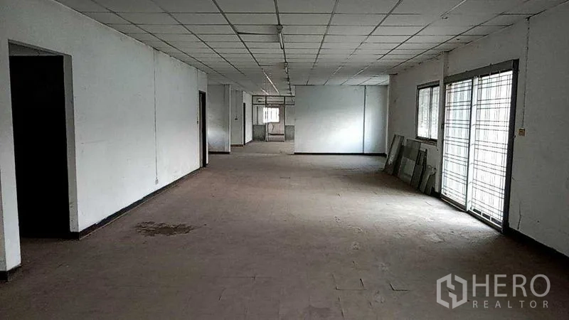 Warehouse for rent in Nakhon Pathom - Empty office area with drop ceiling, tiled floor and barred windows ready for fit-out.