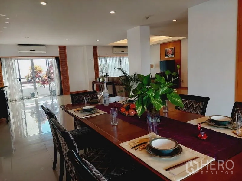 อพาร์ทเมนท์ ให้เช่า - ห้องทานอาหารจัดโต๊ะสำหรับหกที่ พร้อมต้นไม้และประตูเลื่อนออกสู่ระเบียง