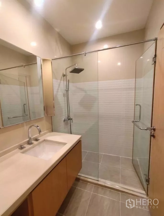 Condominium for rent in Chatuchak, Bangkok - Modern bathroom with glass-enclosed shower and long vanity.