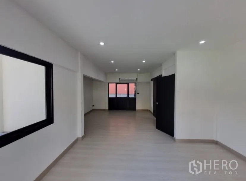 Detached House for rent in Suan Luang, Bangkok - Large flexible room with wood-look flooring, black doors and an air conditioner.
