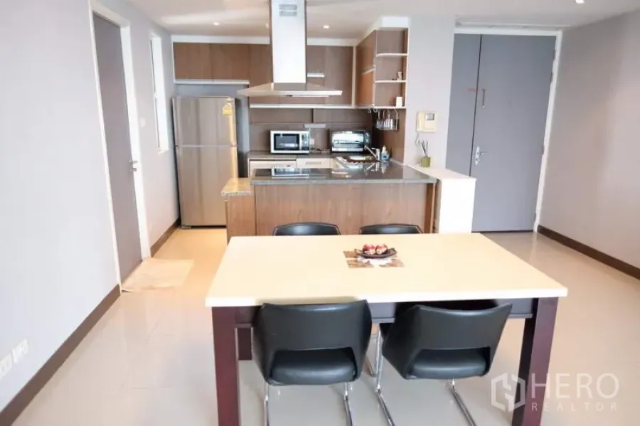 Condominium for rent in Watthana, Bangkok - Open-plan dining and kitchen with island, range hood and wood cabinets in a Bangkok condo.