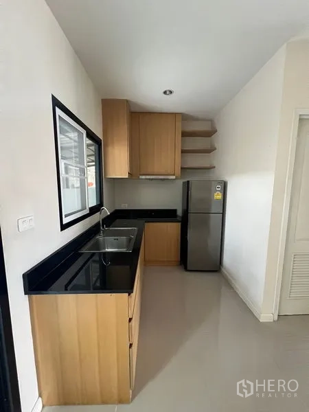 Townhouse for rent in Bang Kapi, Bangkok - Compact kitchen with black granite countertops, double sink and fridge.