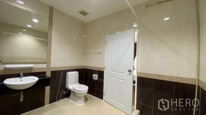Townhouse for rent in Wang Thonglang, Bangkok - Spacious bathroom featuring a large mirror, toilet, and walk-in shower.