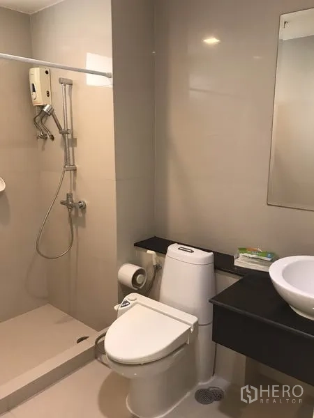 Condominium for rent in Khlong Toei, Bangkok - Compact bathroom with walk-in shower, toilet and vessel sink.