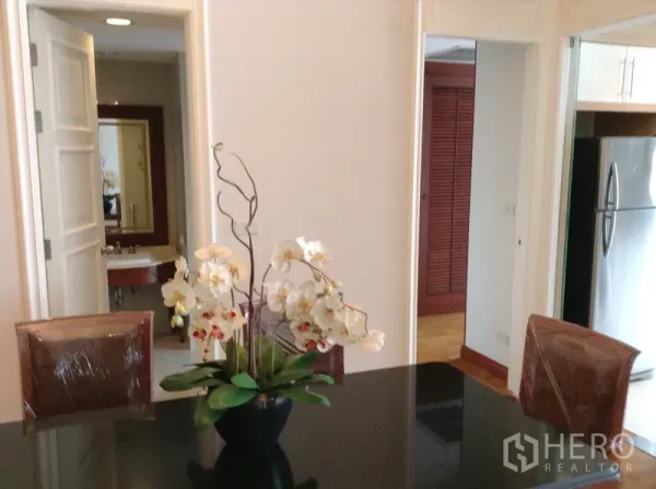 คอนโด ให้เช่าหรือขายในWatthana, Bangkok - พื้นที่ทานอาหาร โต๊ะท็อปสีดำ แจกันกล้วยไม้ มองไปยังครัวและห้องน้ำ