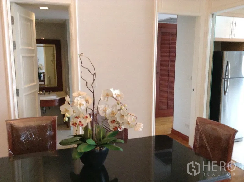 คอนโด ให้เช่าหรือขายในWatthana, Bangkok - พื้นที่ทานอาหาร โต๊ะท็อปสีดำ แจกันกล้วยไม้ มองไปยังครัวและห้องน้ำ