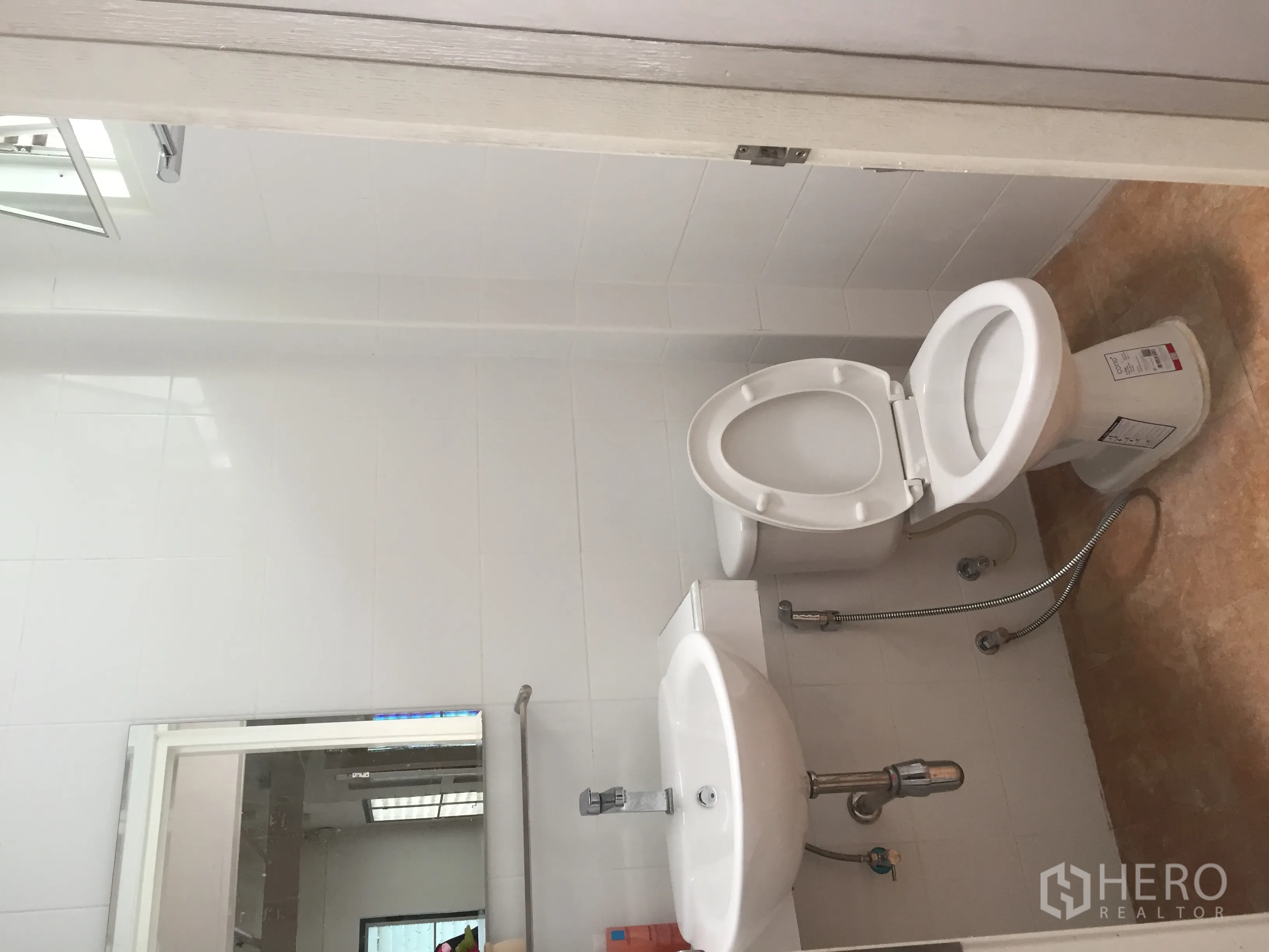 Detached House for rent in Bang Rak, Bangkok - Clean bathroom with white ceramic toilet, basin, wall mirror, and tiled walls.