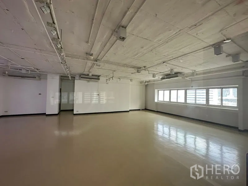 办公空间 出租在Pathum Wan, Bangkok - 明亮的开放式办公室，抛光地面、外露天花和长窗，可见曼谷巴吞旺区城市景观。