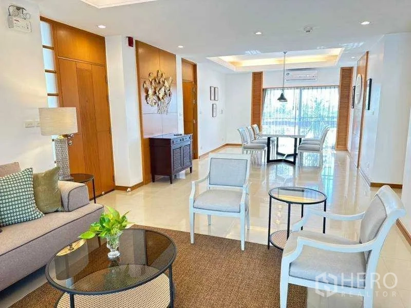 房间 出租 - 明亮的客餐厅一体空间，吊顶灯光，阳台推门与木质元素，位于曼谷沙吞3卧公寓，临近隆比尼地铁站。