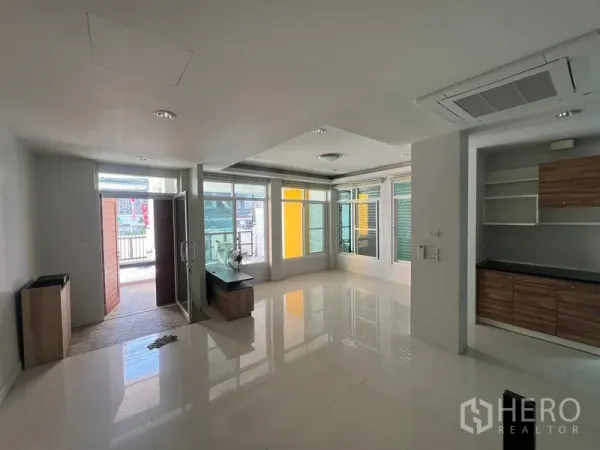 Townhouse for rent in Din Daeng, Bangkok - Bright living room with corner windows, shiny tile flooring and door to the front patio.
