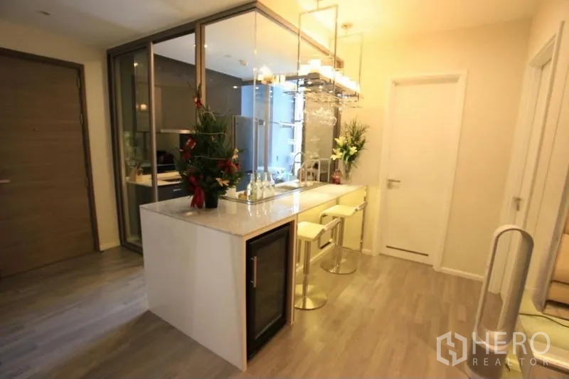 Condominium for rent or sale in Watthana, Bangkok - Kitchen island with wine chiller, bar stools and glass-enclosed cooking area.