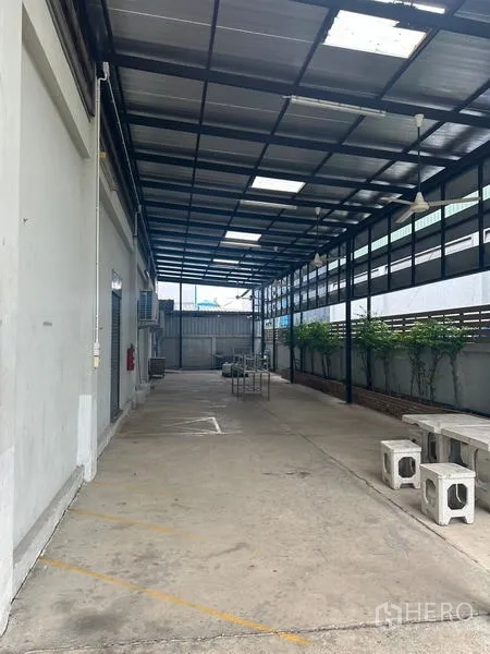คลังสินค้า ให้เช่าหรือขายในLam Luk Ka, Pathum Thani - ลานด้านข้างลึก พื้นคอนกรีตใต้หลังคา พร้อมม้านั่งสำหรับพักของ