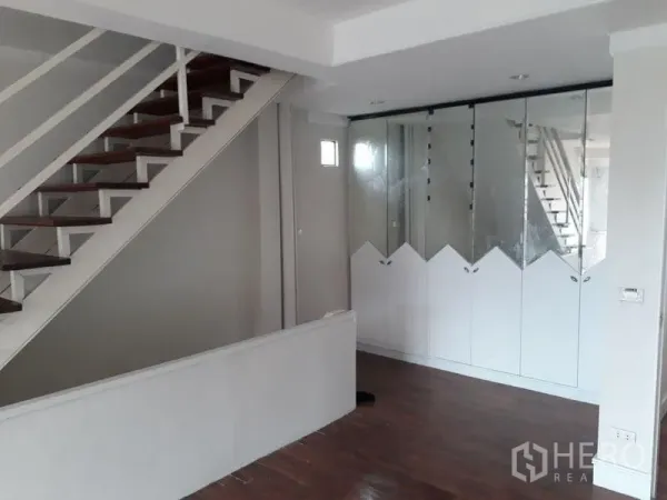 Townhouse for sale in Bang Kapi, Bangkok - Stair hall with wooden steps and built-in mirrored wardrobes beside a white wall.