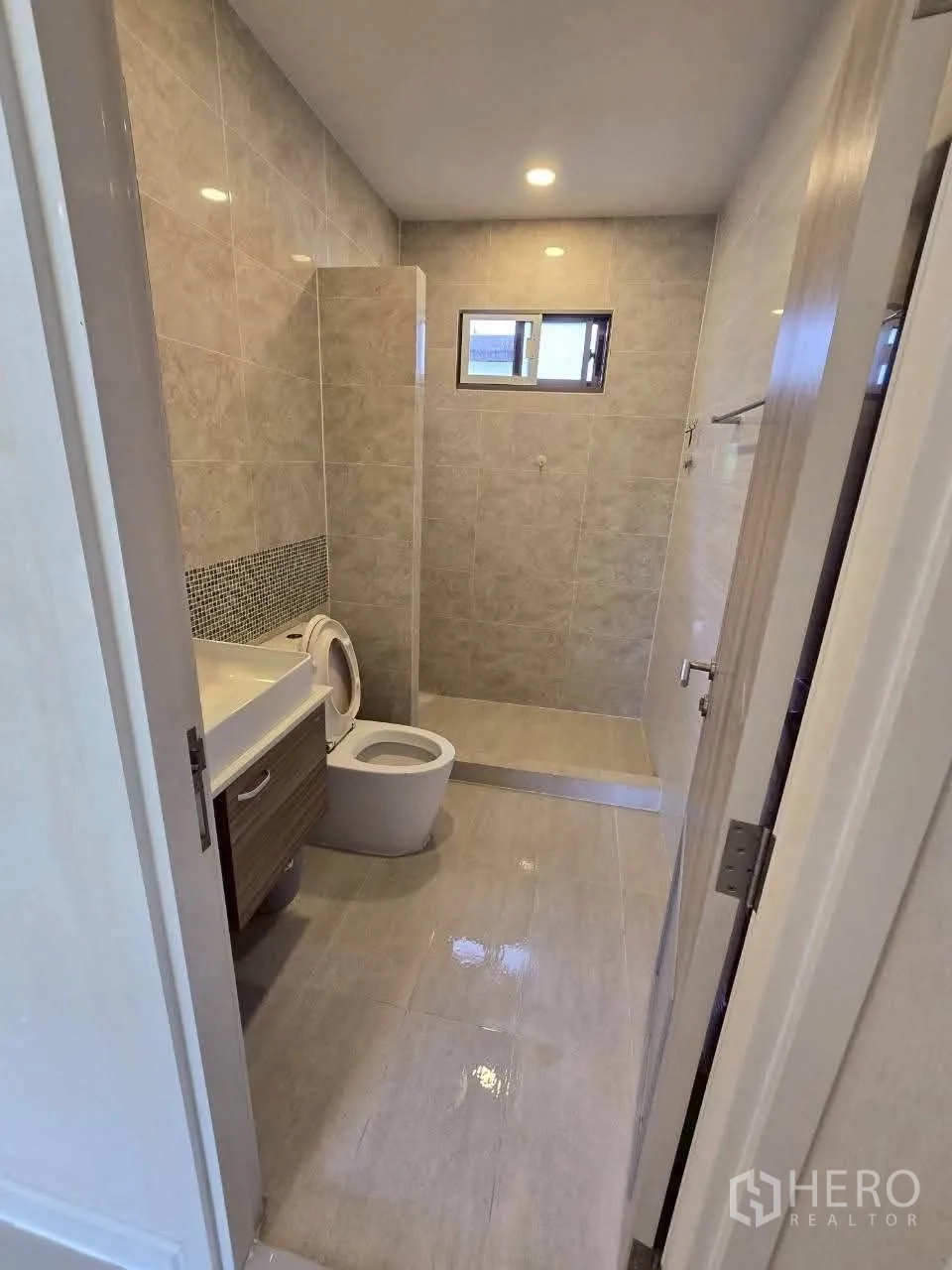 Detached House for rent or sale in Lat Krabang, Bangkok - Tiled bathroom with vanity, toilet, and step-in shower with window.