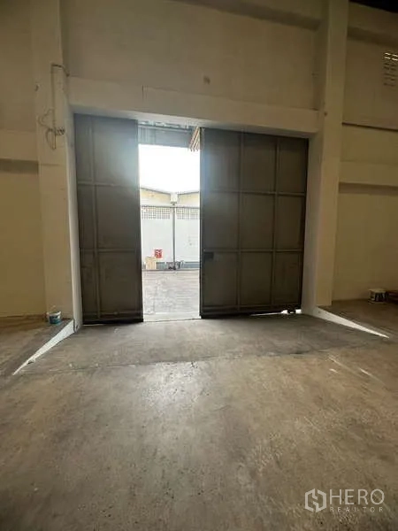 货栈 出租在Suan Luang, Bangkok - 高大的钢制滑门，通向仓库装卸区域。