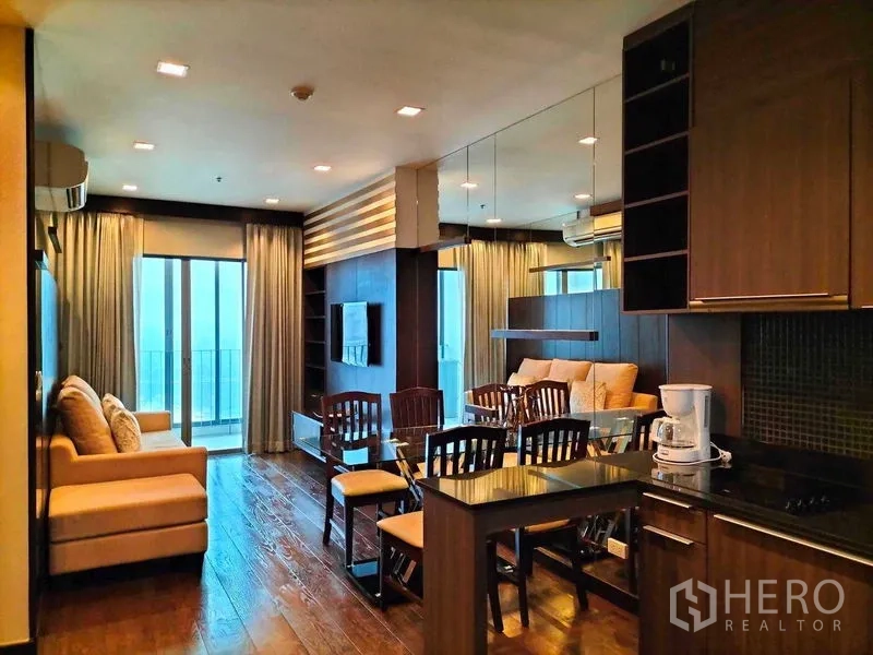 公寓 出租在Ratchathewi, Bangkok - 开放式客厅视角，连接厨房、镜面墙与餐桌并通阳台。