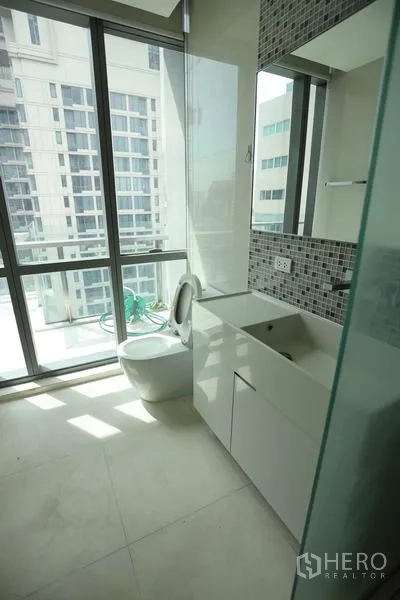 Condominium for rent or sale in Watthana, Bangkok - Modern bathroom with floor-to-ceiling windows, mosaic tile accent, vanity cabinet, and glass shower.