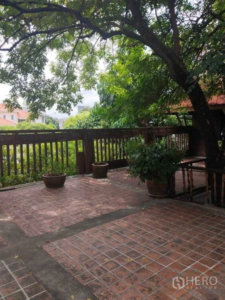 Detached House for rent or sale in Suan Luang, Bangkok - Spacious outdoor terrace with wooden railing, brick tiles, and tree shade.