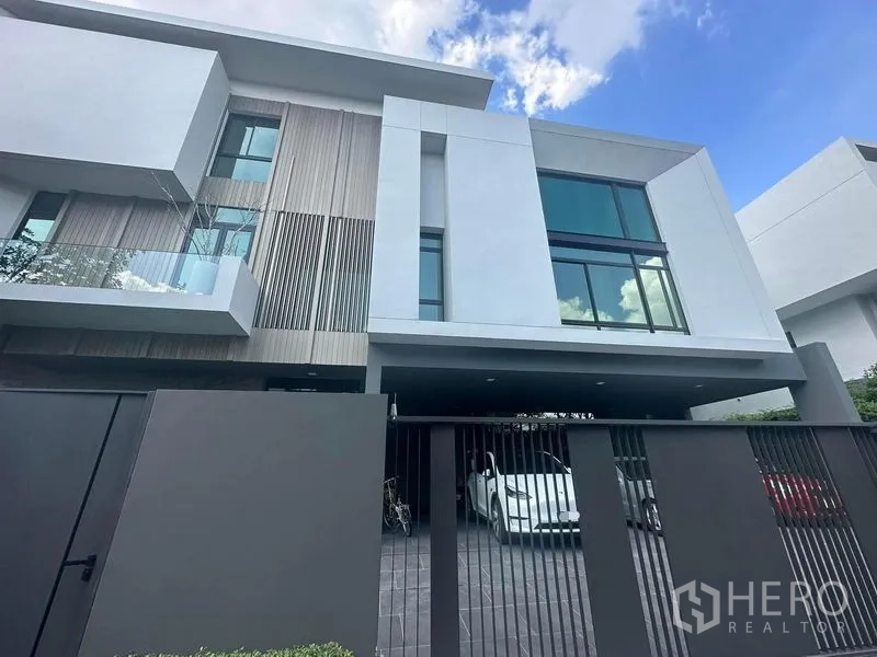Detached House for sale in Saphan Sung, Bangkok - Modern three-storey detached house facade with full-height windows, gated driveway and carport in Bangkok.