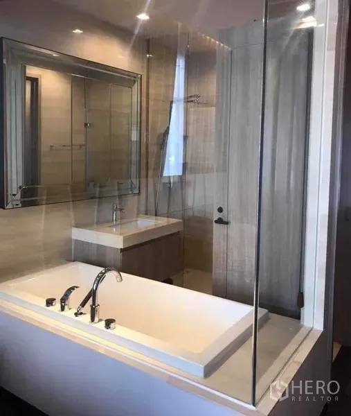 公寓 出租或出售在Watthana, Bangkok - 现代卫浴，带嵌入式浴缸、玻璃隔断、盥洗台与大镜子。