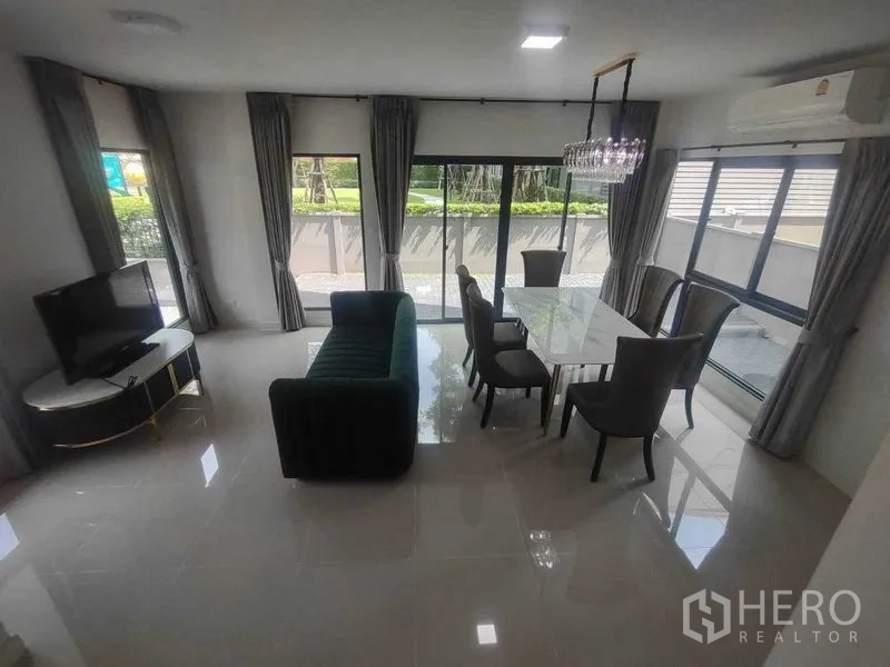 独立式住宅 出租在Khan Na Yao, Bangkok - 开放式客餐厅，配沙发、电视与通高窗户。