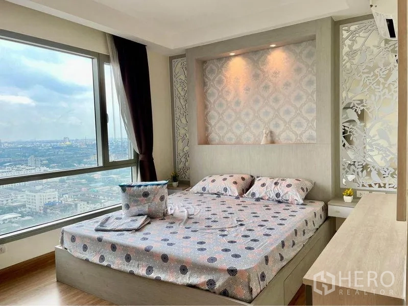 Condominium for rent in Huai Khwang, Bangkok - Corner bedroom with king bed and sweeping city views from picture windows.