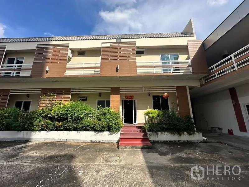 Home Office for rent in Chatuchak, Bangkok - Main building facade with red steps, balconies and greenery.