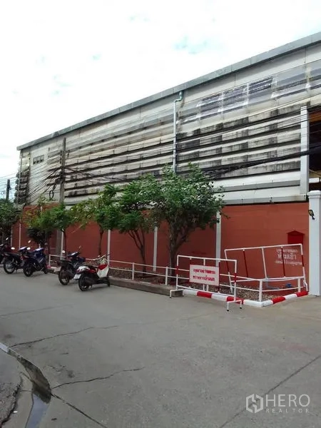 คลังสินค้า ให้เช่าในMueang Samut Prakan, Samut Prakan - มุมมองด้านข้างอาคารโกดังริมถนน มีต้นไม้และมอเตอร์ไซค์จอด