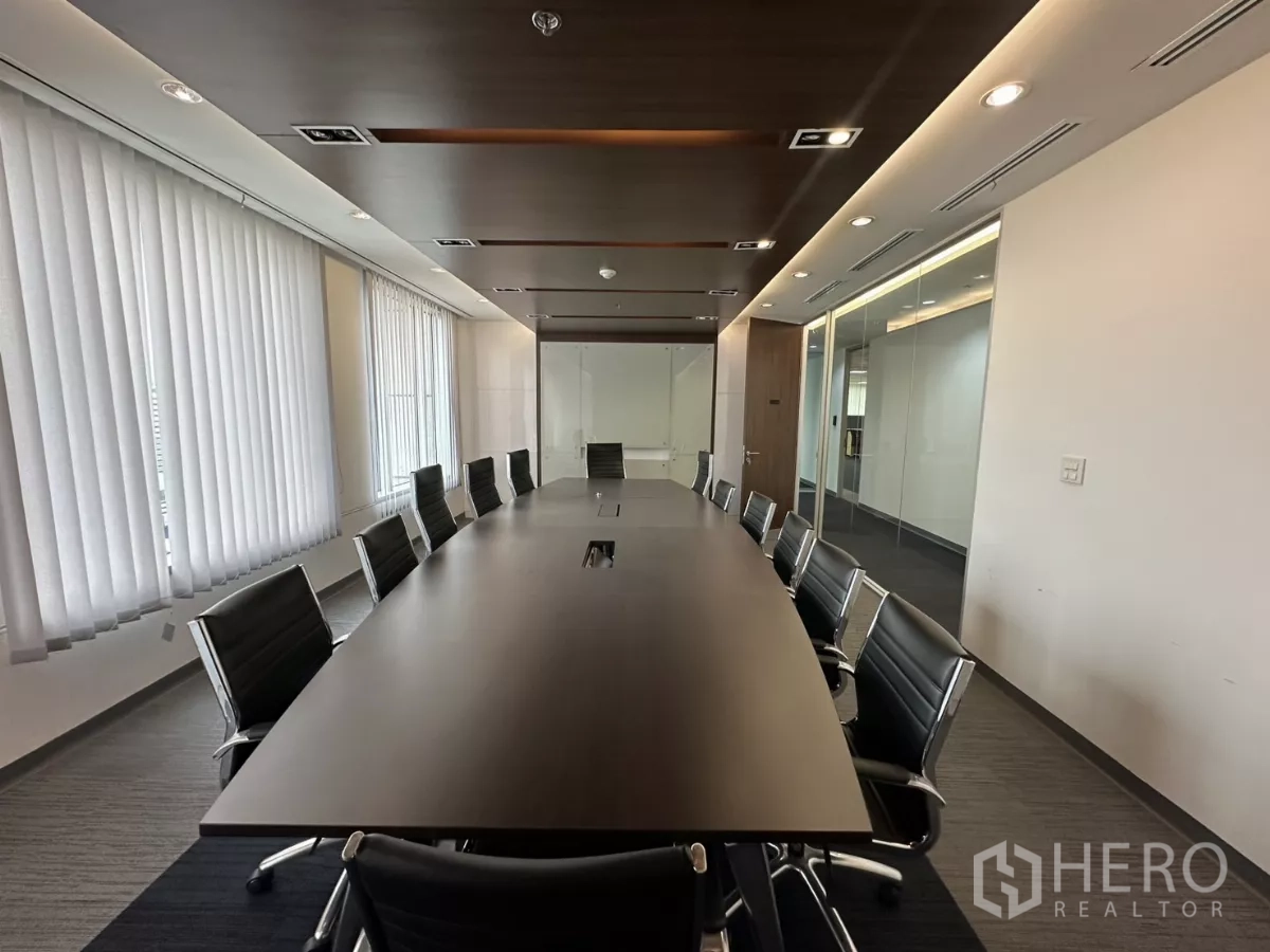 Office Space for rent in Watthana, Bangkok - Large boardroom with a long conference table, around twelve chairs, vertical blinds, wood ceiling accents and glass partitions.