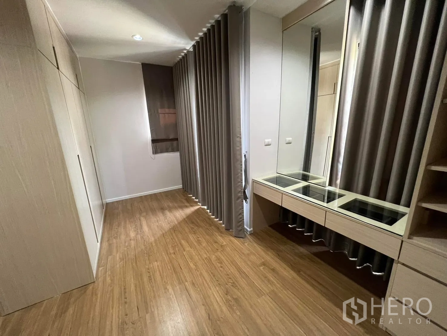 Semi-detached House for rent in Saphan Sung, Bangkok - Dressing area with built-in wardrobes, large mirror, and vanity beside full-length curtains.