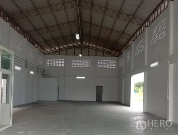 工厂 出租在Lat Lum Kaeo, Pathum Thani - 厂房内部高挑钢架屋顶，通风砖与大型卷帘门开口