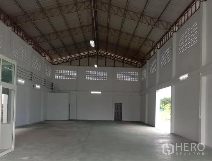 工厂 出租在Lat Lum Kaeo, Pathum Thani - 厂房内部高挑钢架屋顶，通风砖与大型卷帘门开口
