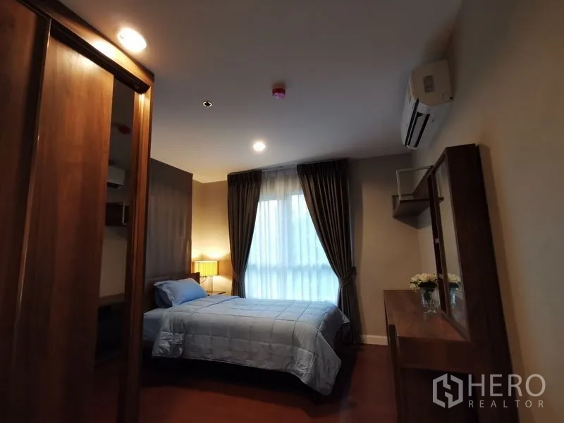 Condominium for rent or sale in Huai Khwang, Bangkok - Bedroom with built-in wardrobe, desk and mirror, air conditioner, and single bed.