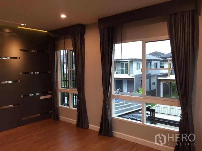 Townhouse for sale in Bang Khae, Bangkok - Corner family room with multiple windows and views of neighboring homes.