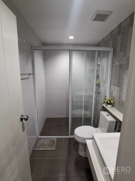 Home Office for rent or sale - Bathroom view showing large sliding glass shower screen and gray floor tiles.