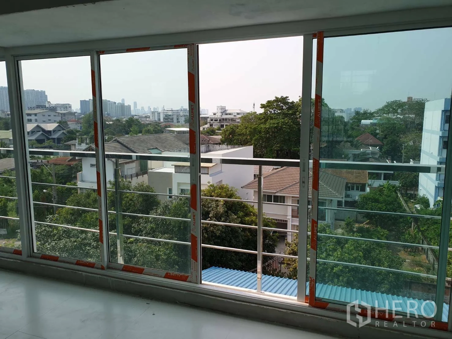 Office Space for rent or sale - Neighborhood and city skyline through sliding glass doors with balcony railing.