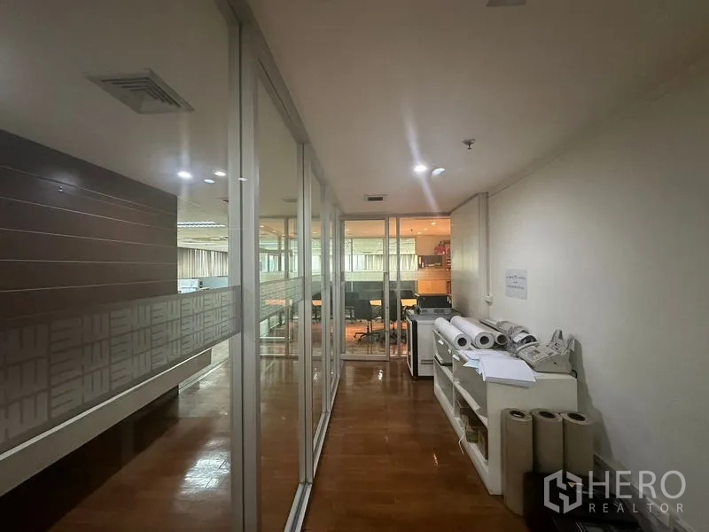 Office Space for rent - Corridor with glass walls and storage shelves holding rolled plans