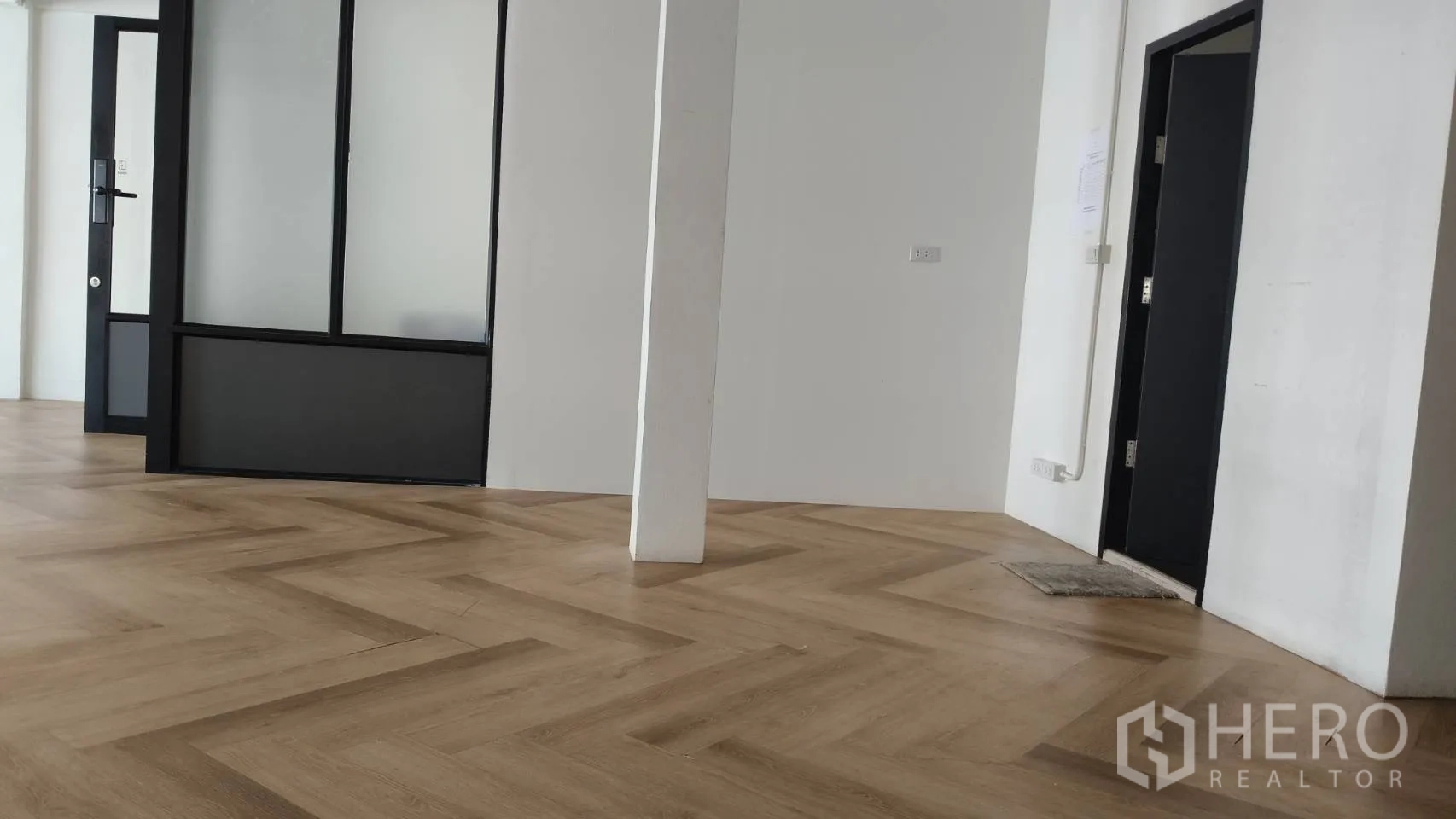 Retail Space for rent in Watthana, Bangkok - Interior corner with a glass partition, central column, and doorway on herringbone flooring.