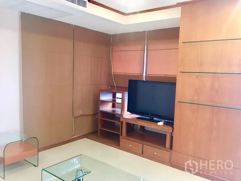 Condominium for rent in Watthana, Bangkok - Cozy living room with built-in wood cabinetry, TV console and glass coffee tables.