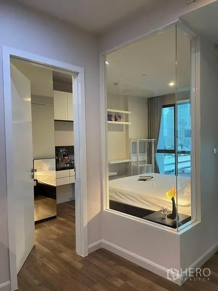 คอนโด ให้เช่าหรือขายในPhra Khanong, Bangkok - มองเห็นห้องนอนผ่านผนังกระจกภายใน พร้อมหน้าต่างวิวเมืองและโคมไฟหัวเตียง