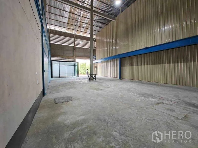 Warehouse for rent in Sam Phran, Nakhon Pathom - Open storage hall with steel roof structure, mezzanine beam and wide roller entry at the far end.