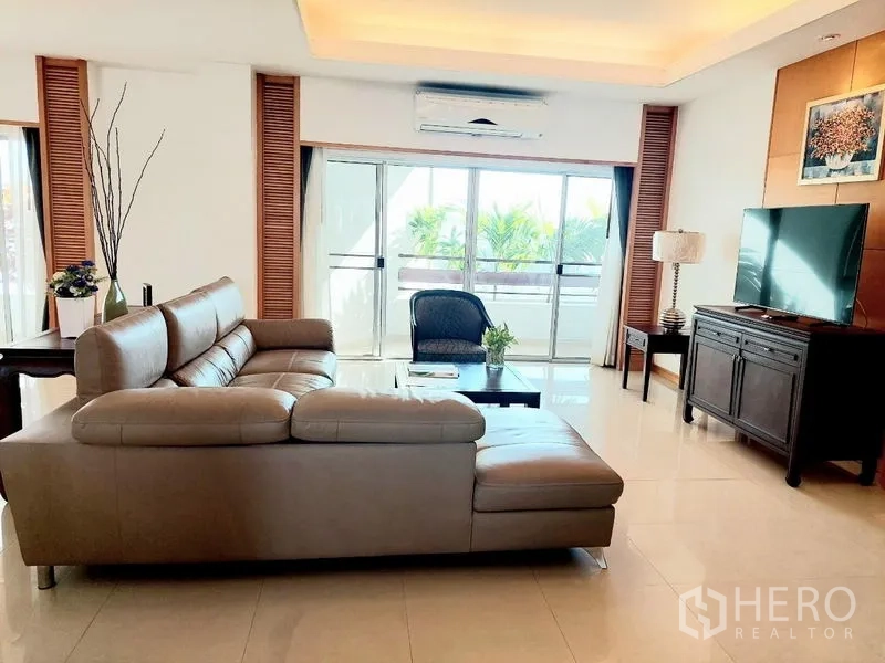 อพาร์ทเมนท์ ให้เช่า - ห้องนั่งเล่นสว่าง โซฟาตัวแอล ตู้ทีวี และประตูกระจกออกระเบียง