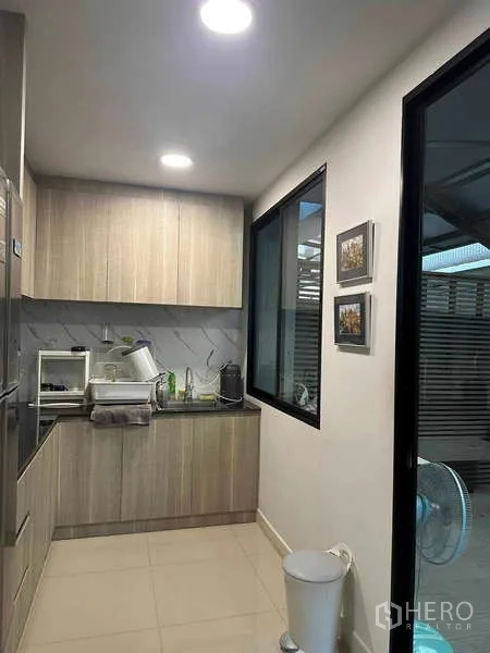 Home Office for rent in Bueng Kum, Bangkok - Compact pantry with light wood cabinets, sink, and window in a clean office setting.